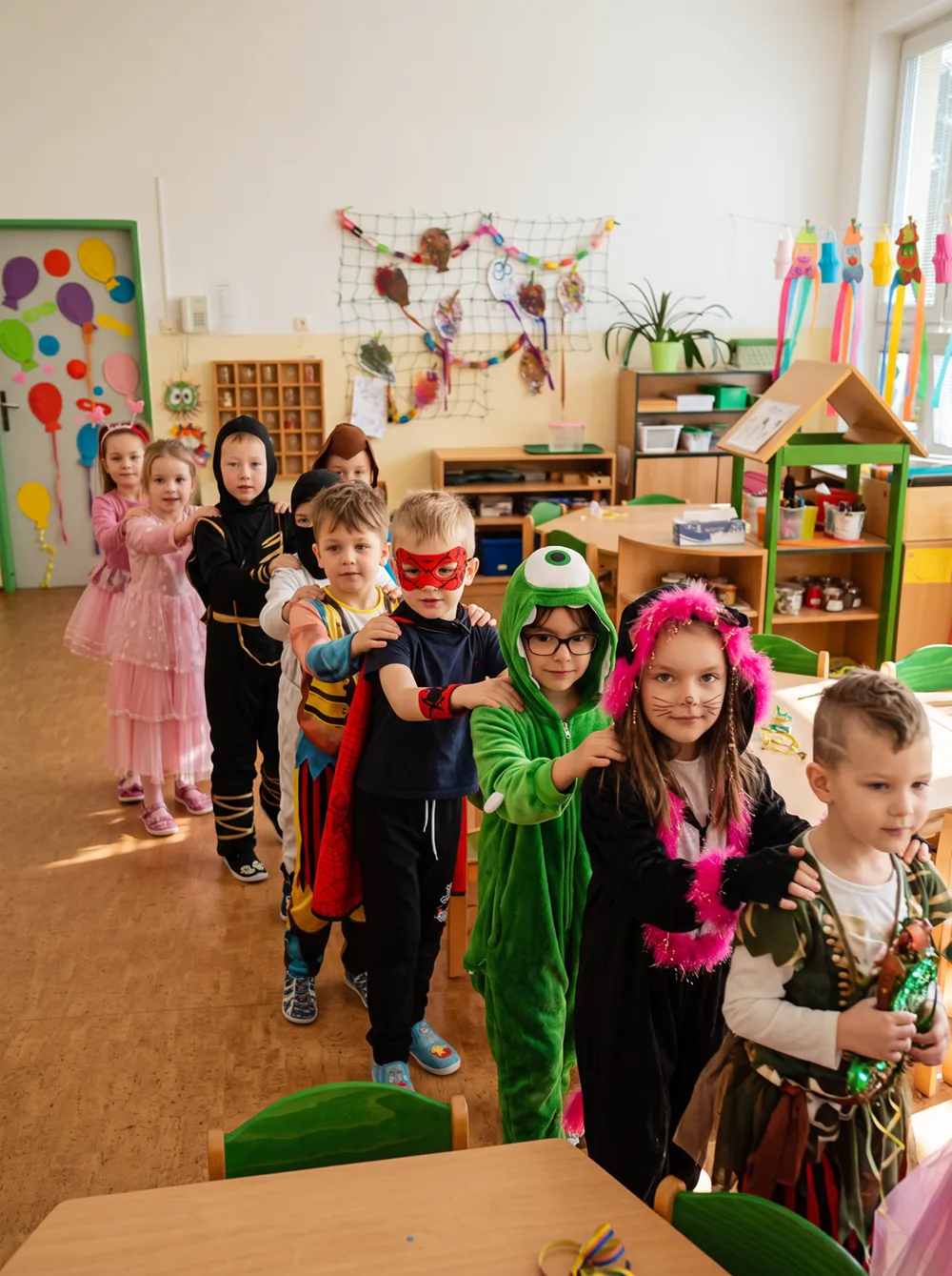 Děti v barevných karnevalových kostýmech ve školce