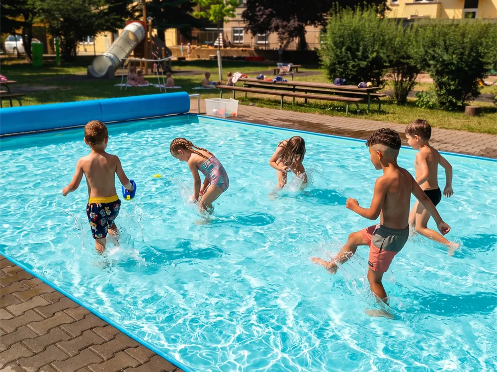 Děti si hrají a cákají ve venkovním bazénu na školní zahradě
